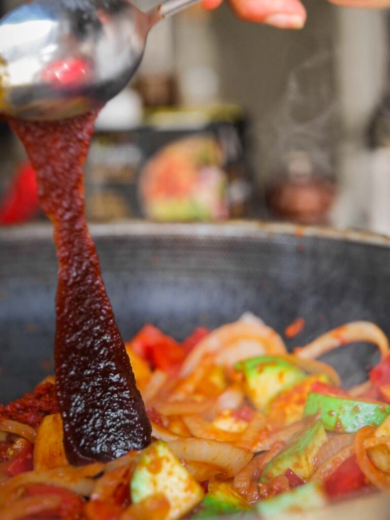 adding gochujang to pan of veggies for pumpkin curry